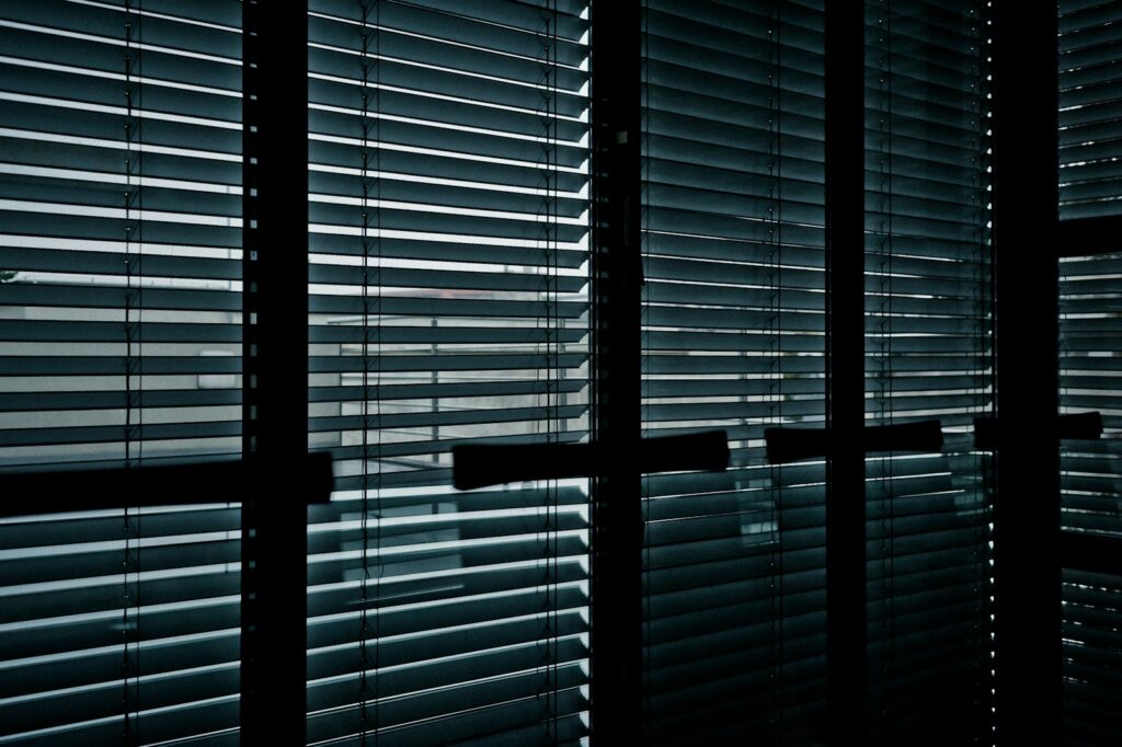 Vertical blind kantor putih terpasang pada jendela ruang kerja modern