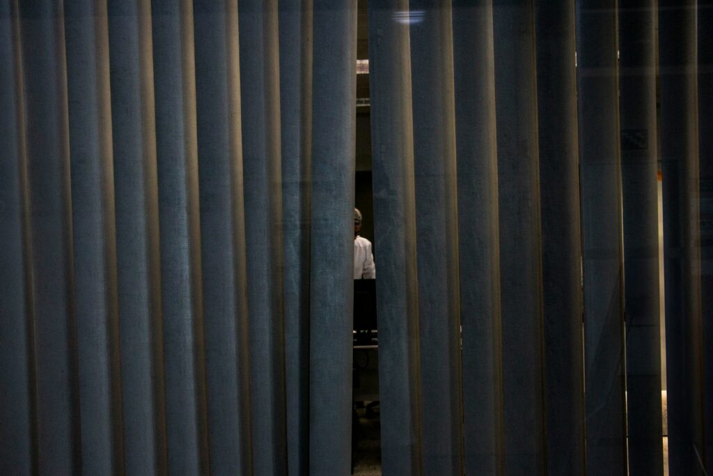 Sosok terlihat samar di balik vertical blind yang tertutup